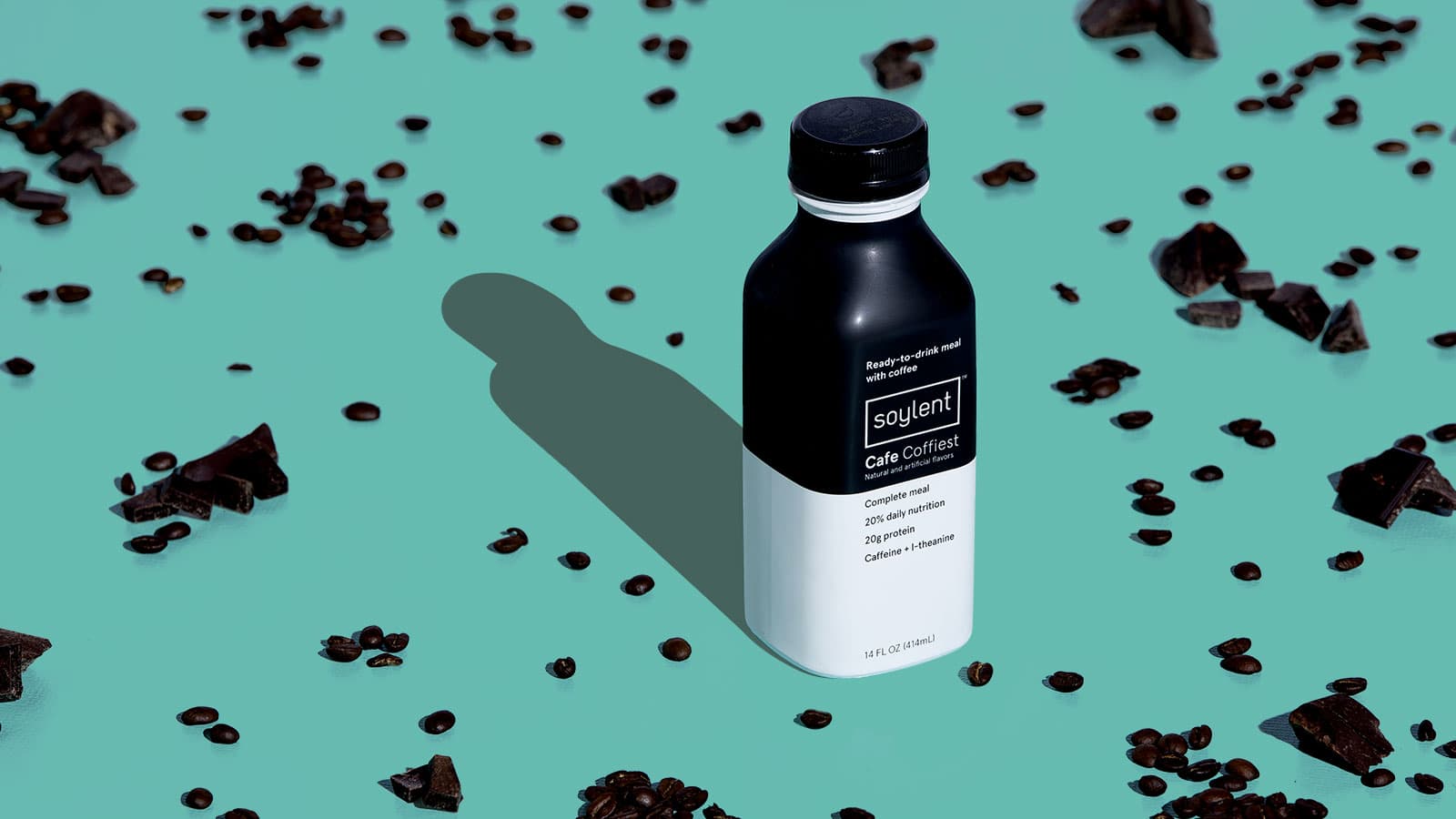 A bottle of Soylent Cafe Coffiest surrounded by coffee beans and chocolate chunks.