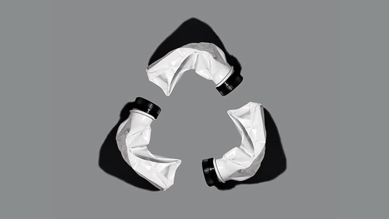 Three empty bottles of Soylent Drink in the shape of a recycling icon.