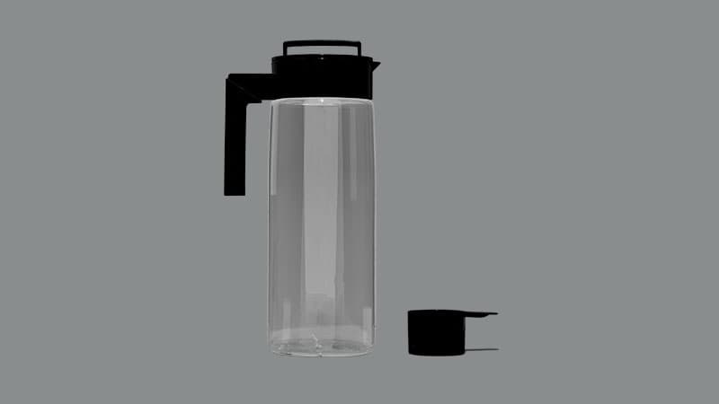 A clear plastic pitcher with black lid and a black plastic measuring scoop.