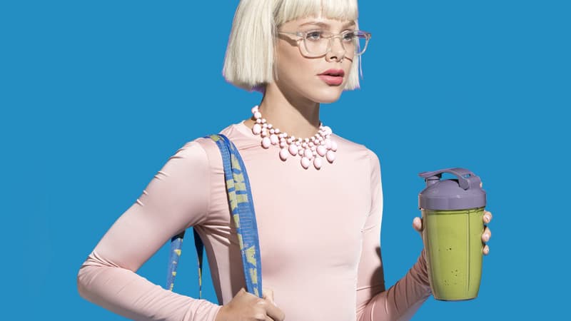 Woman holding a travel mug with a Soylent Powder smoothie.
